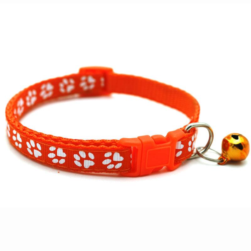 Orange pet bell collar with white paw-print pattern, adjustable buckle, and bell