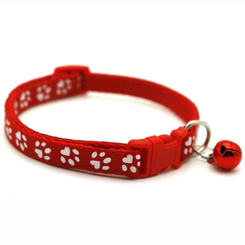 Red pet bell collar with white paw-print pattern, adjustable buckle, and red bell
