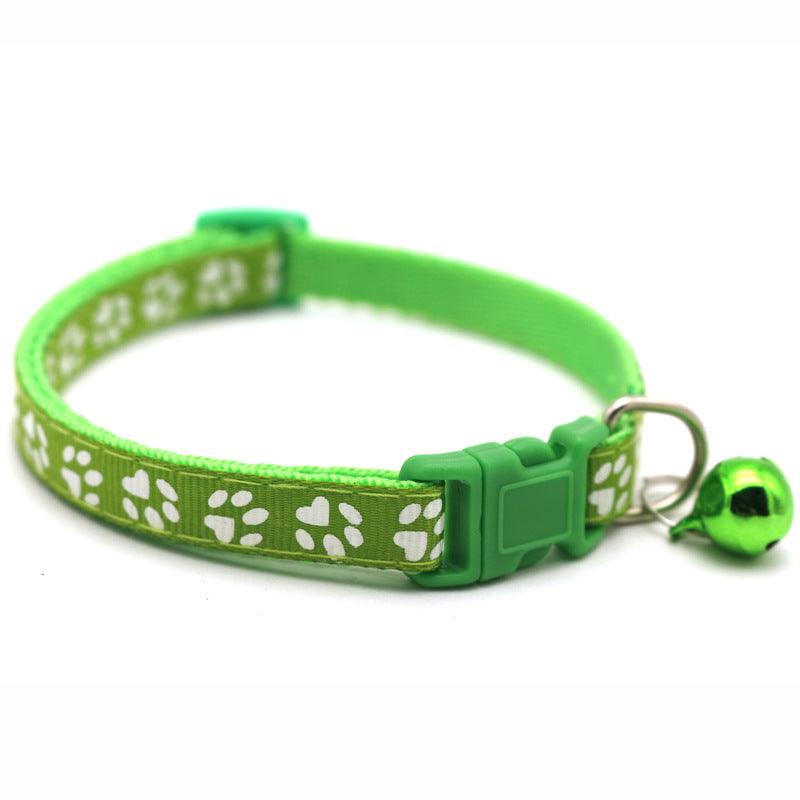 Green pet bell collar with white paw prints, plastic buckle, and small hanging bell