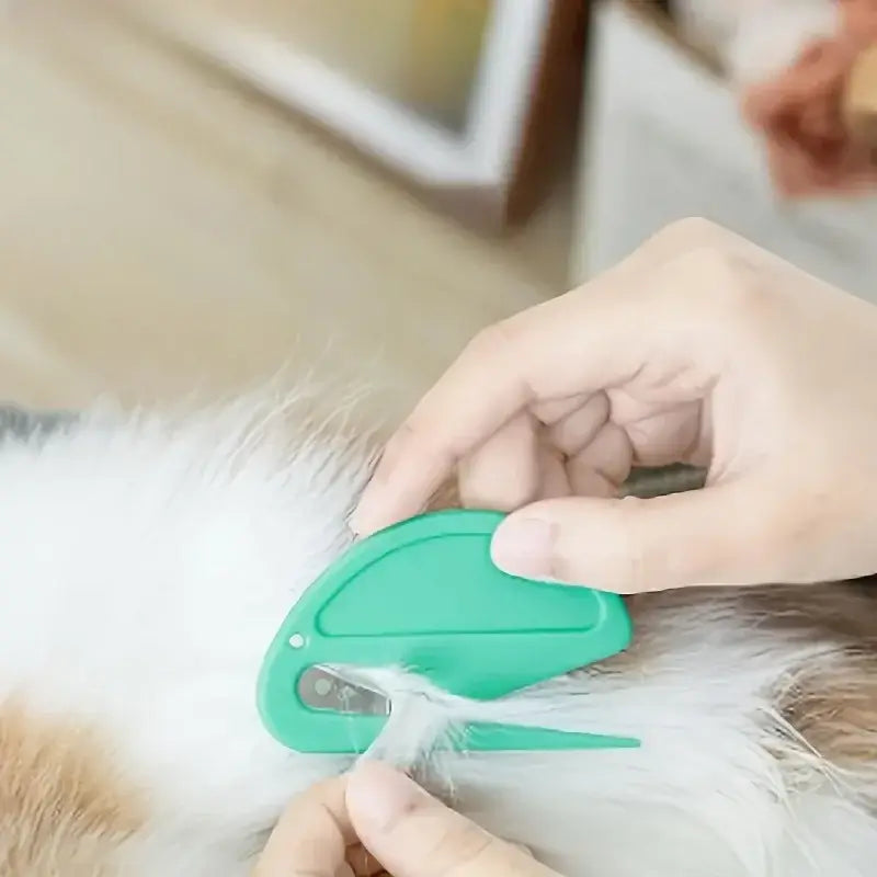 Green knotting grooming comb with blade, held against fluffy dog fur