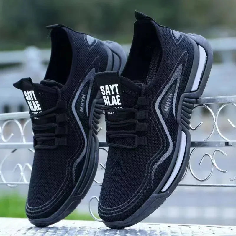 Black slip-on athletic sneakers with thick sole, black logo patch, and side stripe trim