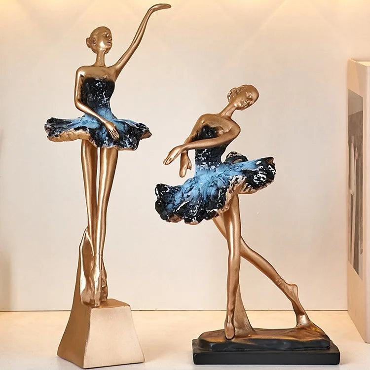 Two blue ballet dancer resin sculptures with gold bodies, blue tutus, on black bases