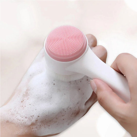 Pink 3D silicone face brush head on a white handle, held by hand over cleanser foam