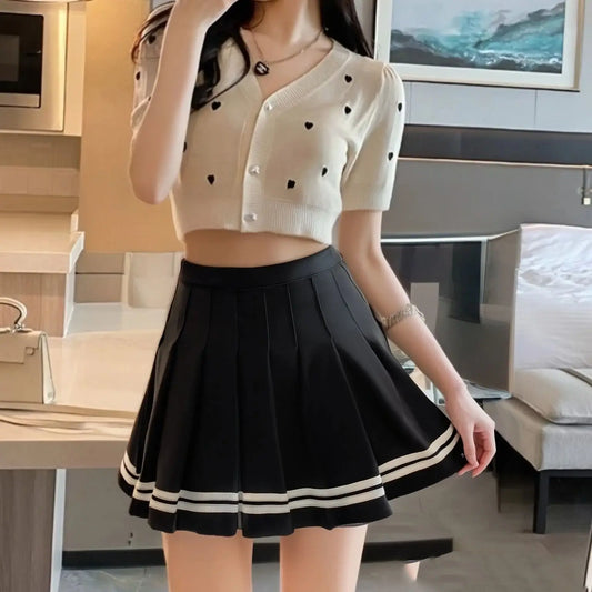 Pleated A-line mini skirt in black with layered panels and double white striped hem
