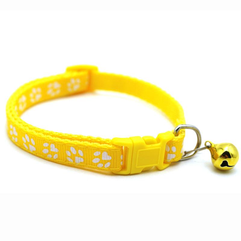 Yellow pet bell collar with white paw-print pattern, buckle clasp, and small bell