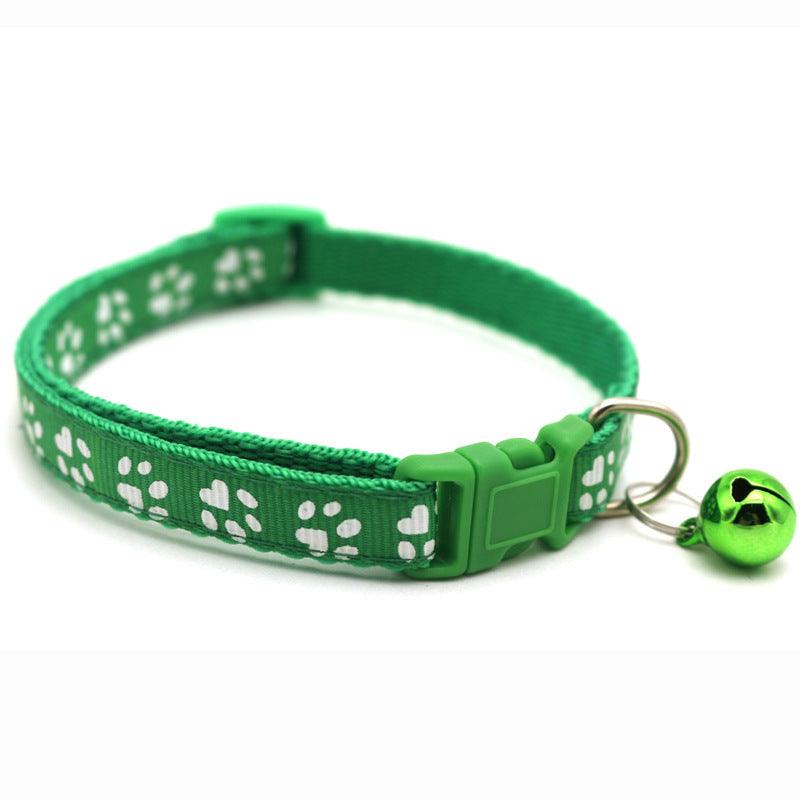 Green pet bell collar with white paw prints, plastic buckle, and small hanging bell
