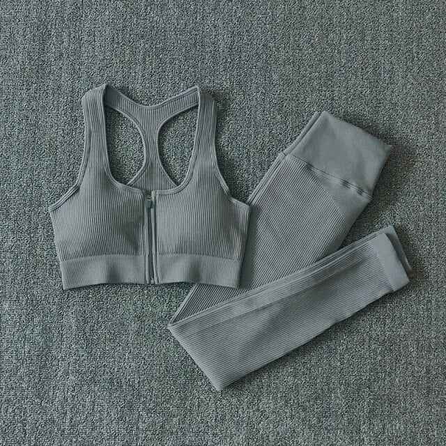 Gray seamless yoga set with zip-front sports bra and ribbed leggings, flat lay.