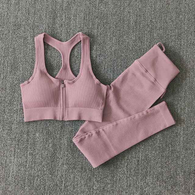 Dusty pink seamless yoga set with zip-front sports bra and ribbed leggings, flat lay.