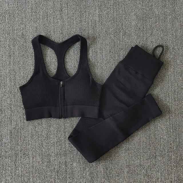 Black seamless yoga set with zip-front sports bra and ribbed leggings, flat lay.
