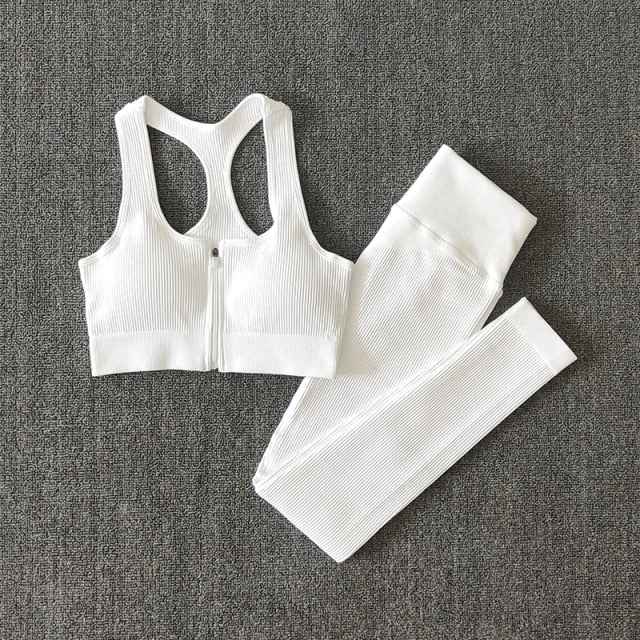 White seamless yoga set with zip-front sports bra and ribbed leggings, flat lay.
