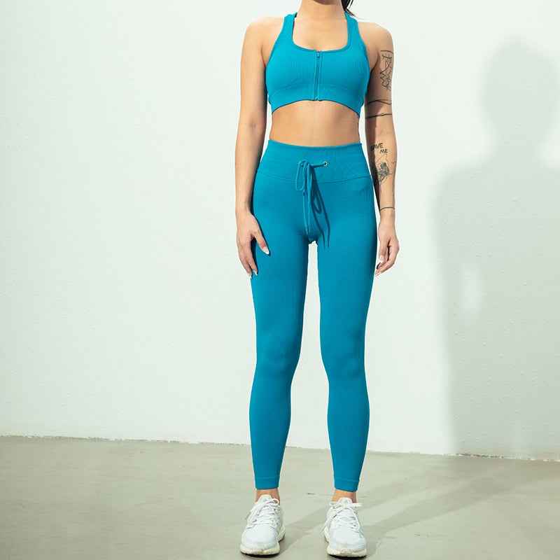 Turquoise seamless yoga set with zip-front sports bra and drawstring leggings, front view.